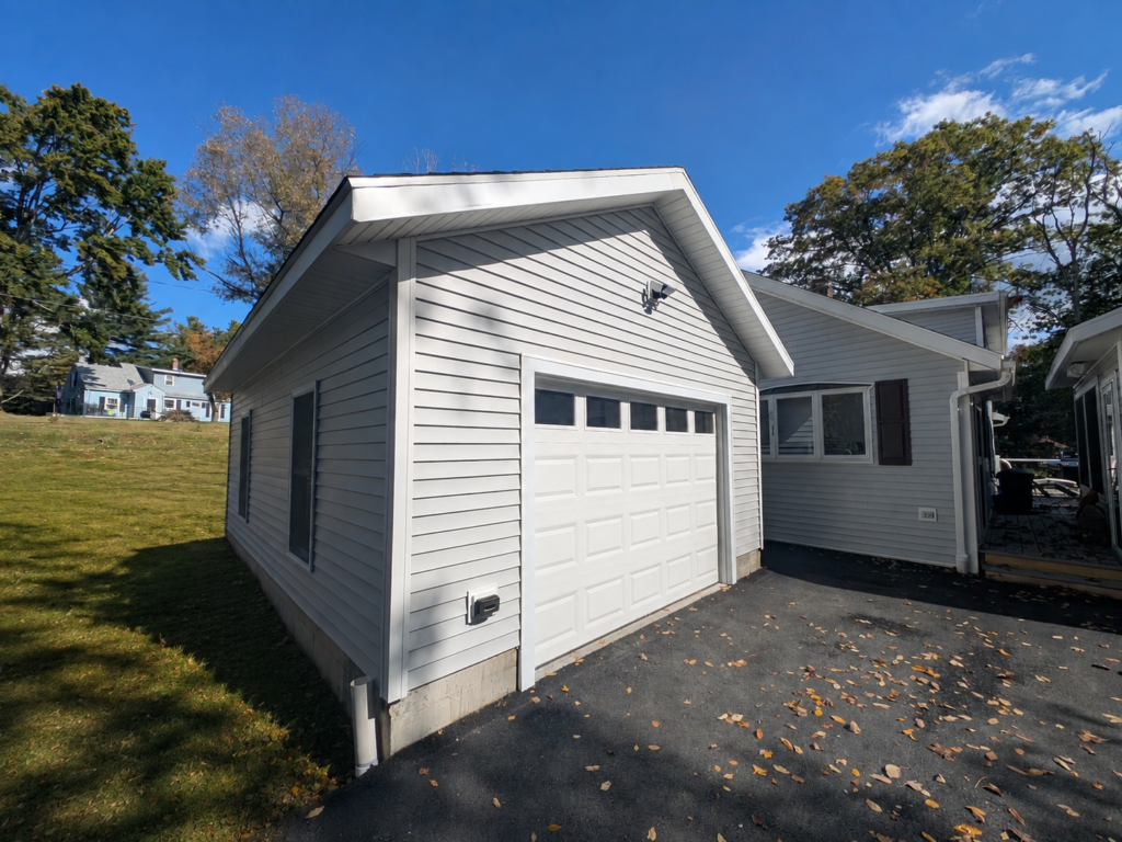 Completed lakeside garage addition with coordinated siding, trim, roofline and driveway.