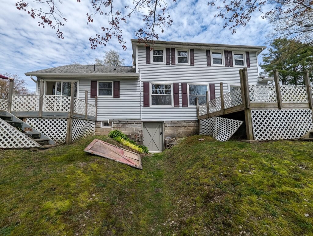 Rear of the lakeside home before construction with two separate aging wood decks
