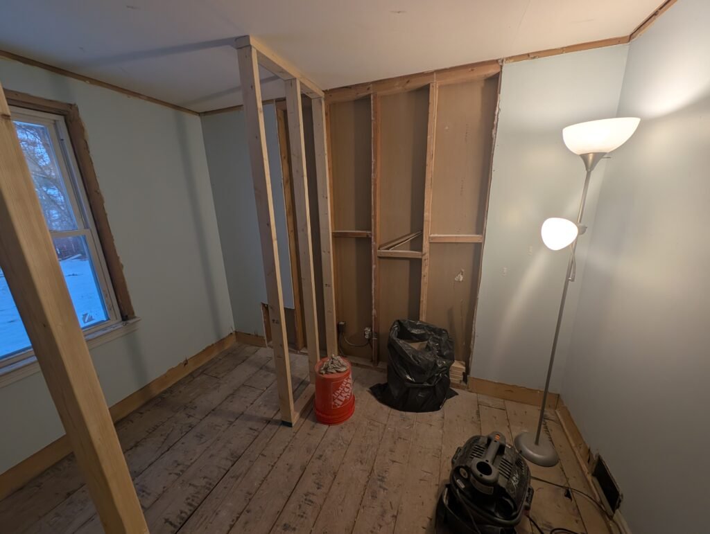 Former bedroom during conversion with walls opened and new bathroom partitions being framed