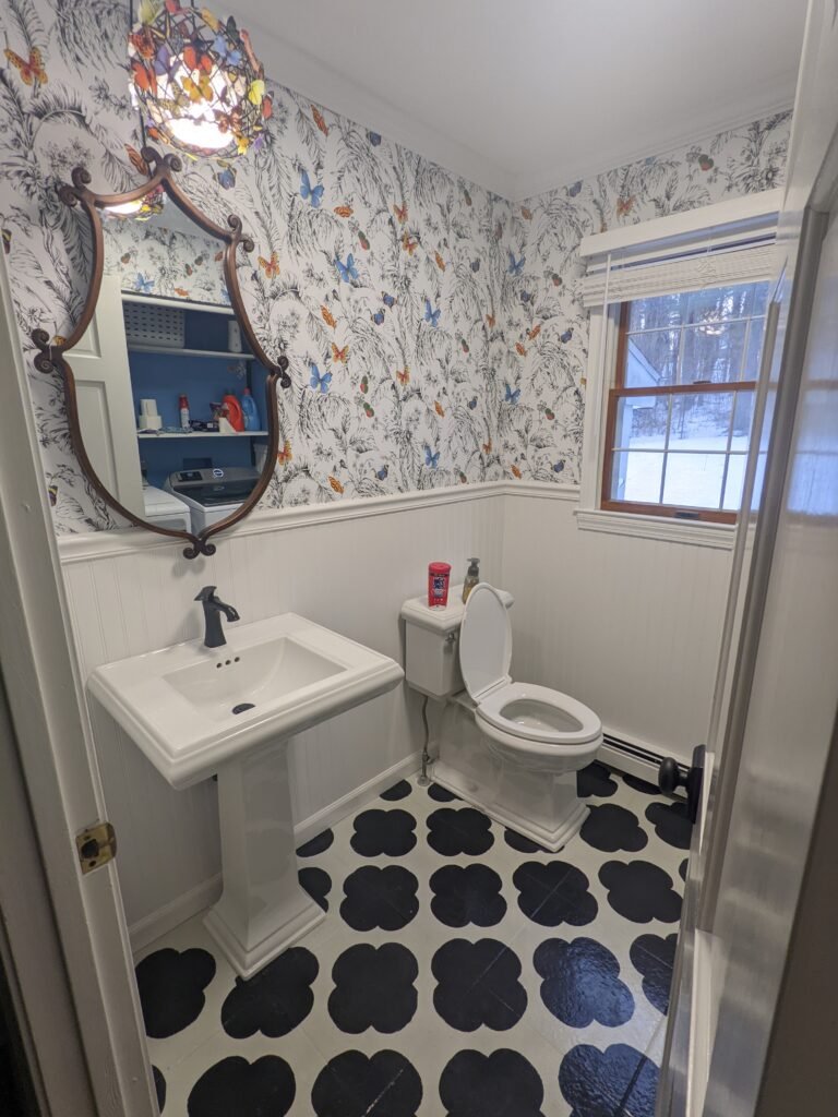 Completed Butterfly Bath with butterfly wallpaper, white beadboard, a pedestal sink and black-and-white epoxy flooring