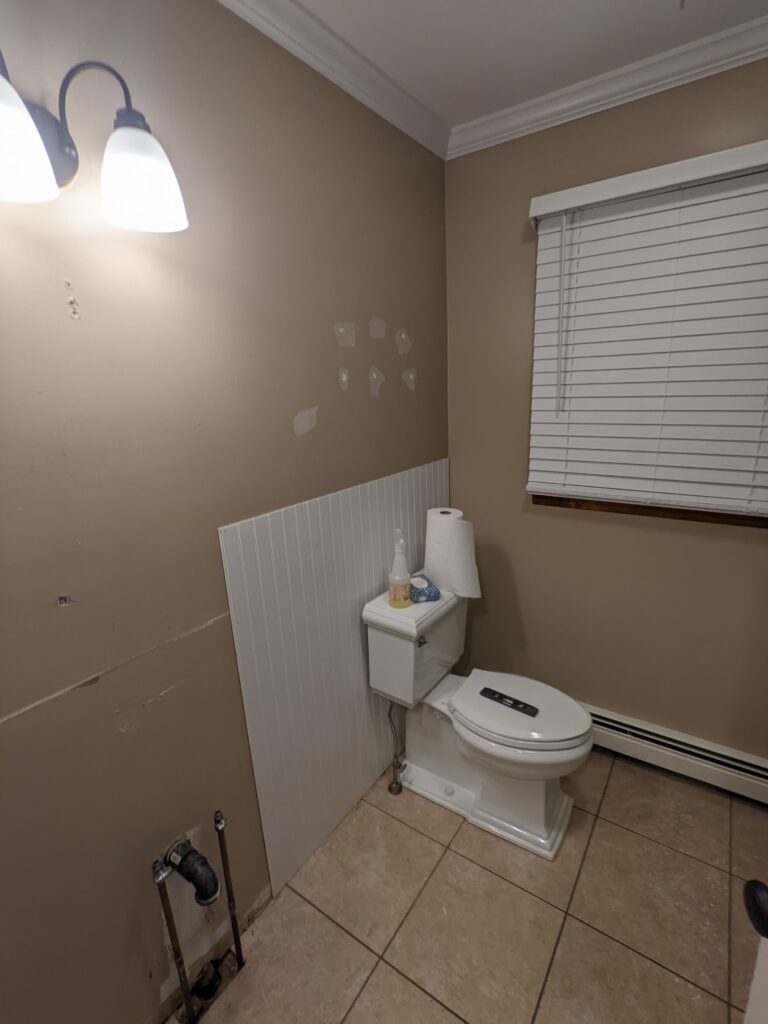 Bathroom area before remodeling with beige walls, tile flooring and the original fixture layout