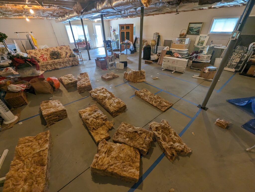 Open unfinished basement with exposed insulation, ductwork, steel supports and concrete flooring