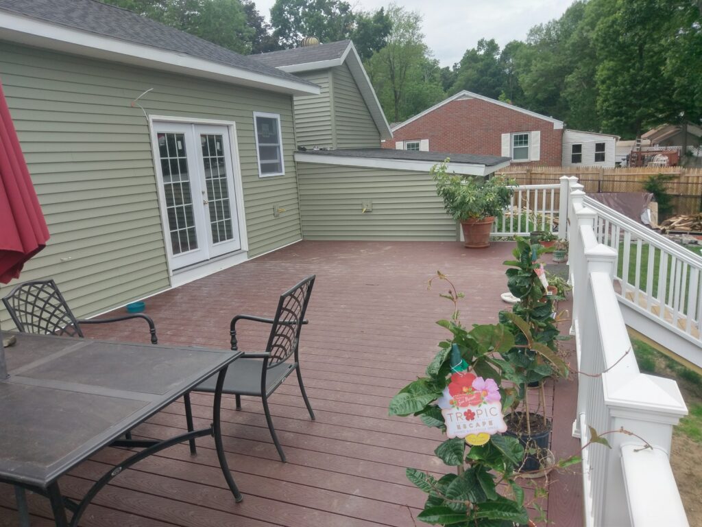 Completed rear deck with composite decking and white railings beside the home addition