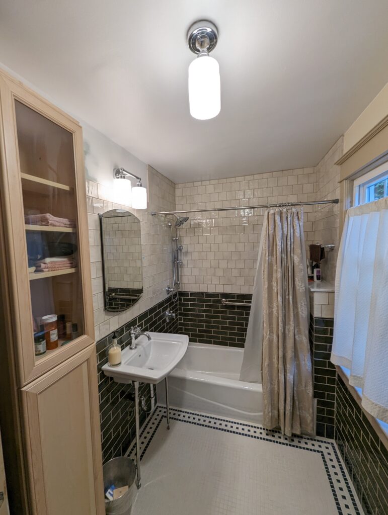 Completed vintage tile bathroom remodel with green glazed wall tile, white subway tile, a wall-mounted sink and bathtub