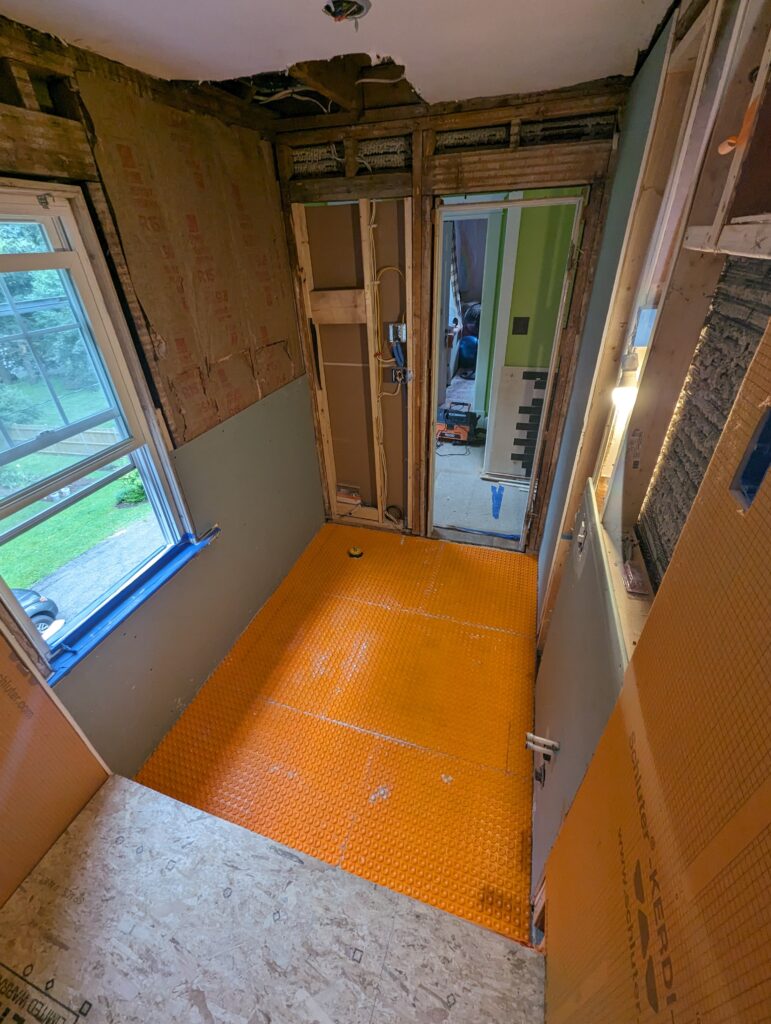 Bathroom during reconstruction with walls opened for new plumbing and the floor membrane installed