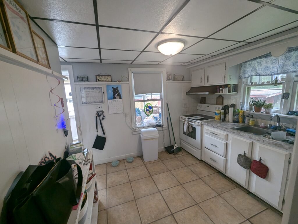 Kitchen during demolition with exposed framing, wiring and flooring before reconstruction