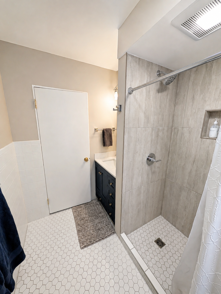 Completed walk-in shower with stone-look porcelain tile, recessed niche and hexagonal mosaic shower floor